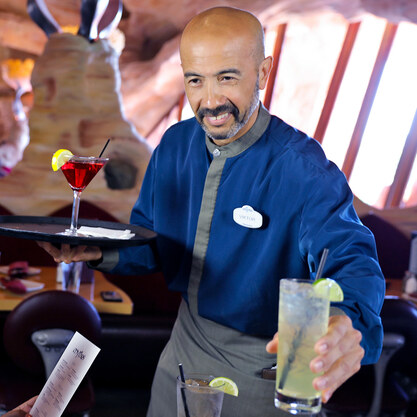 A man is serving a drink to a guest in a restaurant.