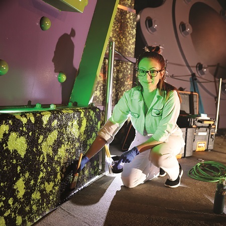 Technical Services Team Member painting a set of an attraction.