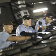 a woman wearing glasses in a white jumpsuit kneels while painting a piece of an attraction at night.
