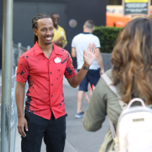 two people, a smiling adult and child, riding in a bright red, colorful attraction.